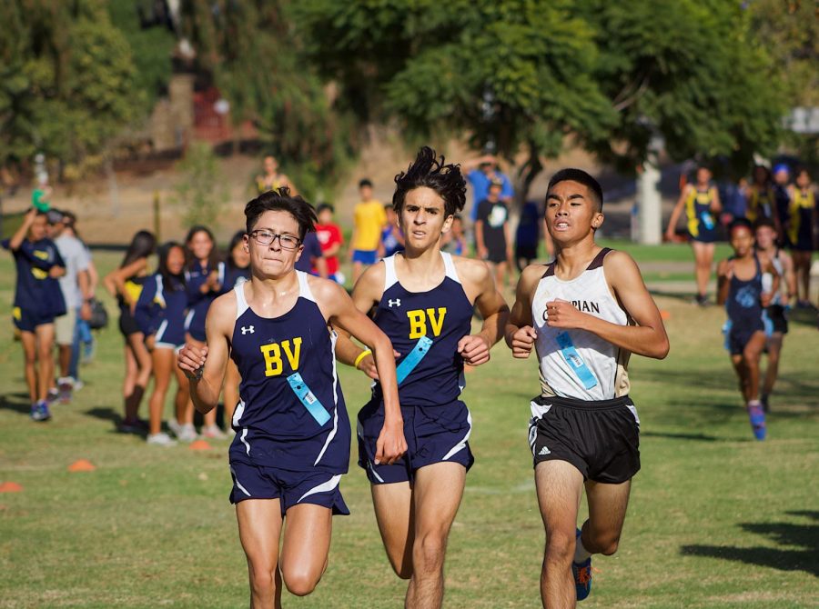 Boys Varsity Cross Country freshmen Samuel Hernandez [left] and senior Christian Mason [middle] run their last stretch to the finish line. Partnered by and Olympian runner to the far right. XC had to run two laps with all teams at Rohr Park on Nov. 9th. 