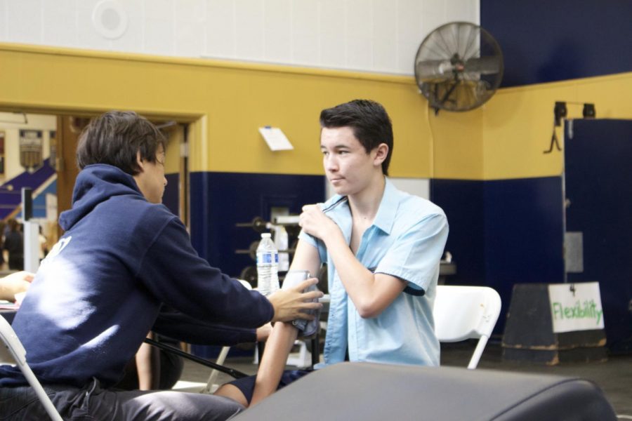 Member of the Sports Medicine club and volunteer senior Kevin Tang administers a blood pressure test on a student getting a sports physical.