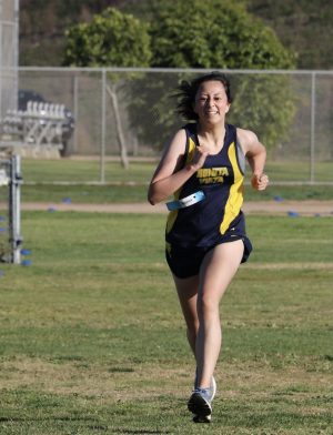 Varsity cross country runner and junior Kiara Sandoval speeds up as she reaches the finish line. The race path was delineated with colored cones and white lines.
