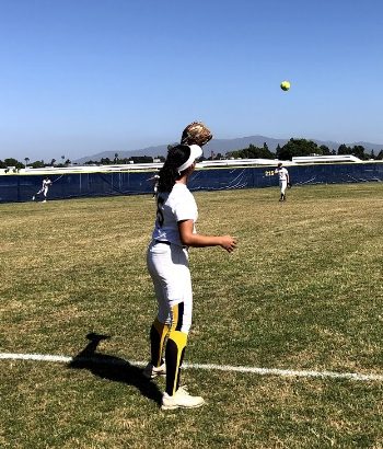 Senior Sophia Estrada received a pitch from fellow senior Nicole Hill. Their warm-up occured right before their game against Cathedral Catholic High School.