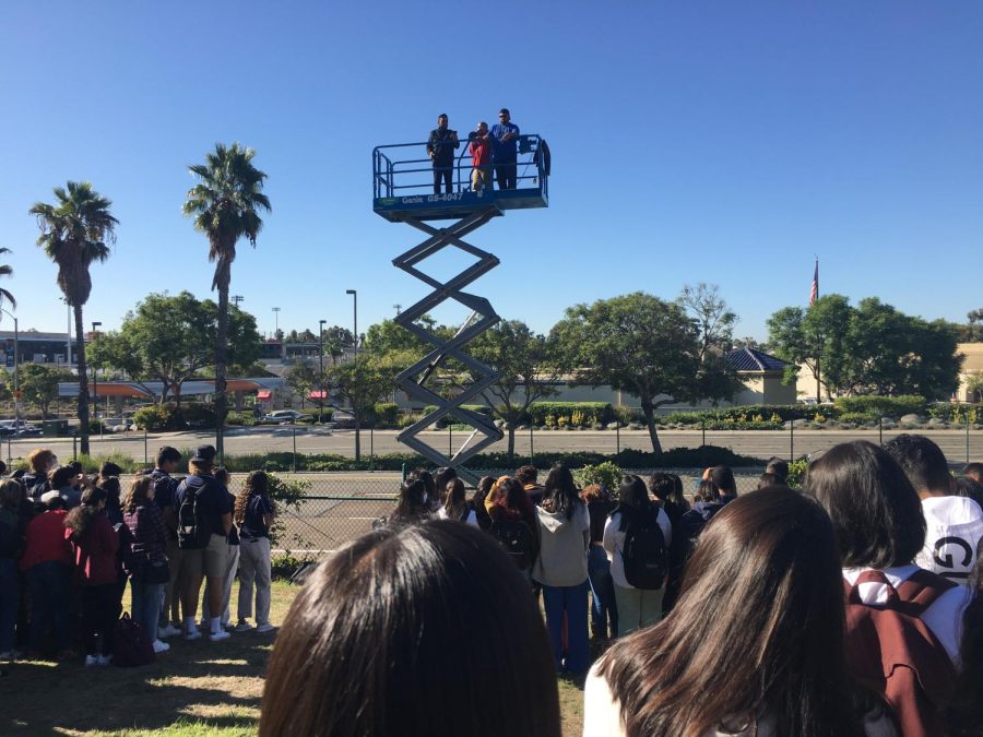 Yearbook Advisor Gabriel Garcia prepares to take the senior panoramic atop an aerial lift. The students bellow were organized into the number 22 to represent their graduating class