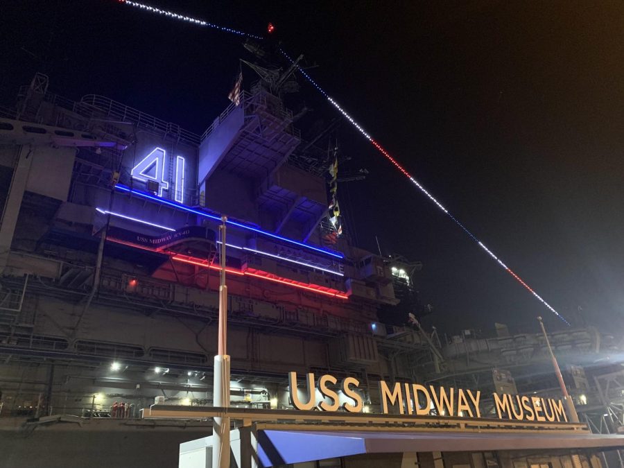 The lights of the USS midway create a stark contrast from the dark of the night. Its exterior sported traditional red, white and blue colors on the night of homecoming. 