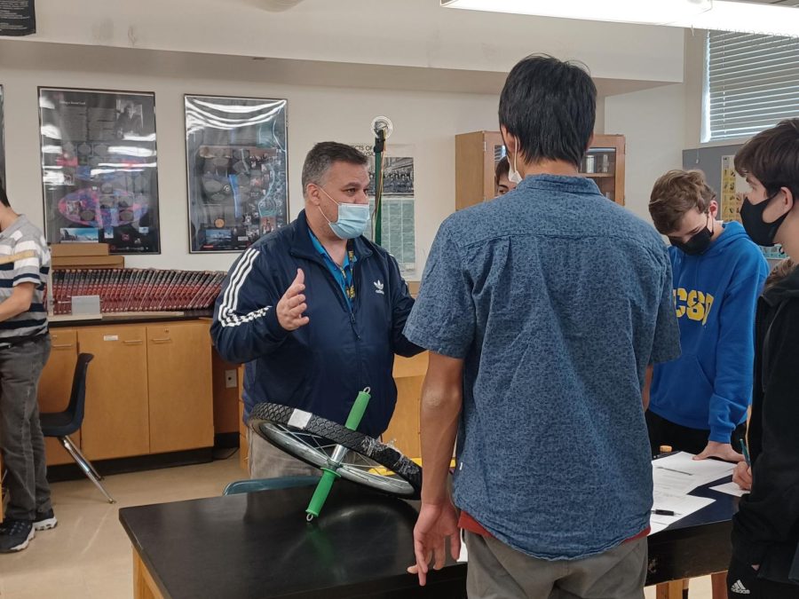 AP Physics teacher Elan Hiller returns after contracting COVID-19 and quarantining for six days at home. Hiller resumes instruction as usual, explaining the physics of a wheel.