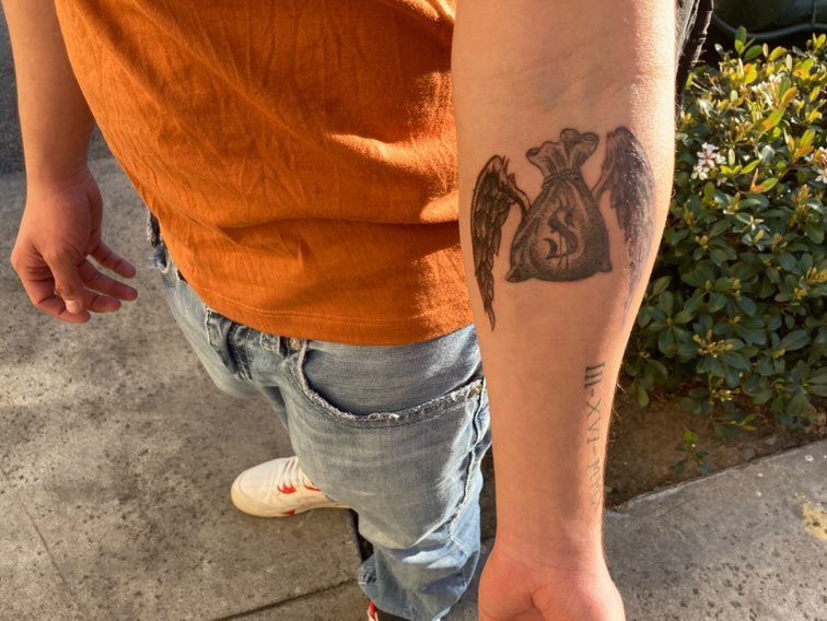 As light shines upon his forearm, sophomore Javier Escalante shows one of his tattoos. The tattoo depicts a money bag with wings. The tattoo is a homage for Escalantes friend.