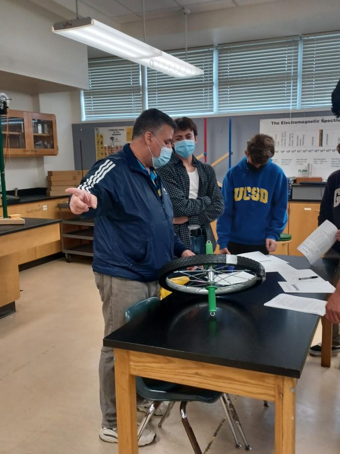 Advanced Placement (AP) and International conducts lab with students. He is explaining the physics of the wheel to the small group of students at the table.