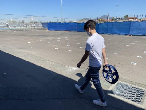 Senior Benjamin Romero walks to the
bathroom during fifth period with
the bathroom pass for Autoshop. The
pass is a blue hubcap provided by
Autoshop teacher Jose Levya.