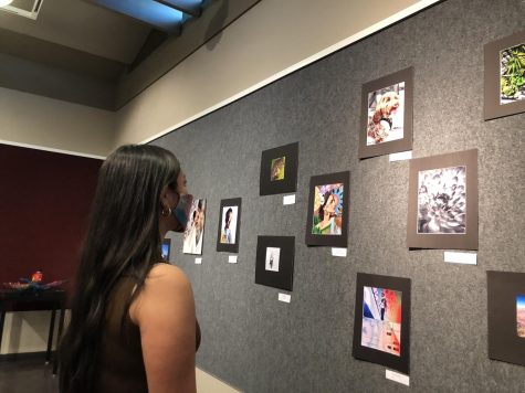 AP Photography student and junior Sophia Morgan examines her featured photo in the Student Art Exhibition at the Bonita Museum on April, 8. Her piece showcases her dads best friends dog as a part of a pop color assignment.