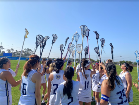 Varsity girls Lacrosse team all strategize with a plan for the next half of the game. Before heading back onto the field they shout, intensity on three! to encourage each other.