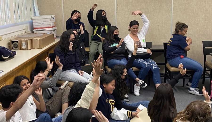 International Baccalaureate (IB) raise their hands after an IB parent asks, How many have cried because of the IB program?. IB students laugh as they see every IB student in the room raise their hand.