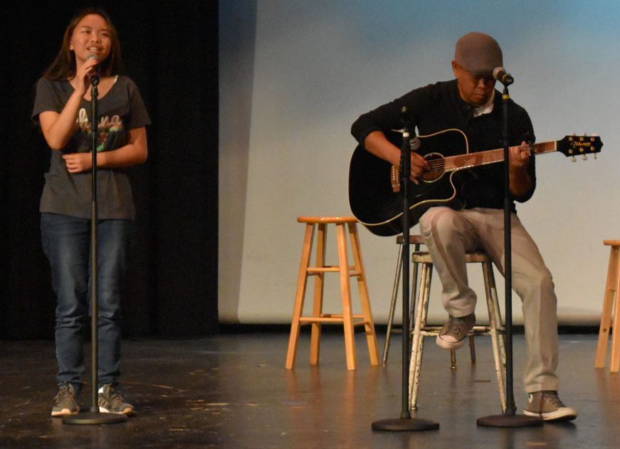 Junior and alto section leader Evelyn Sugapong (left) and her father Errol Sugapong (right) perform a duet of You Are the Reason at the Vocal Music Departments (VMD) open mic night in the Bolles theater on Sept. 14. This was one of various performances by different members and former members of VMD.