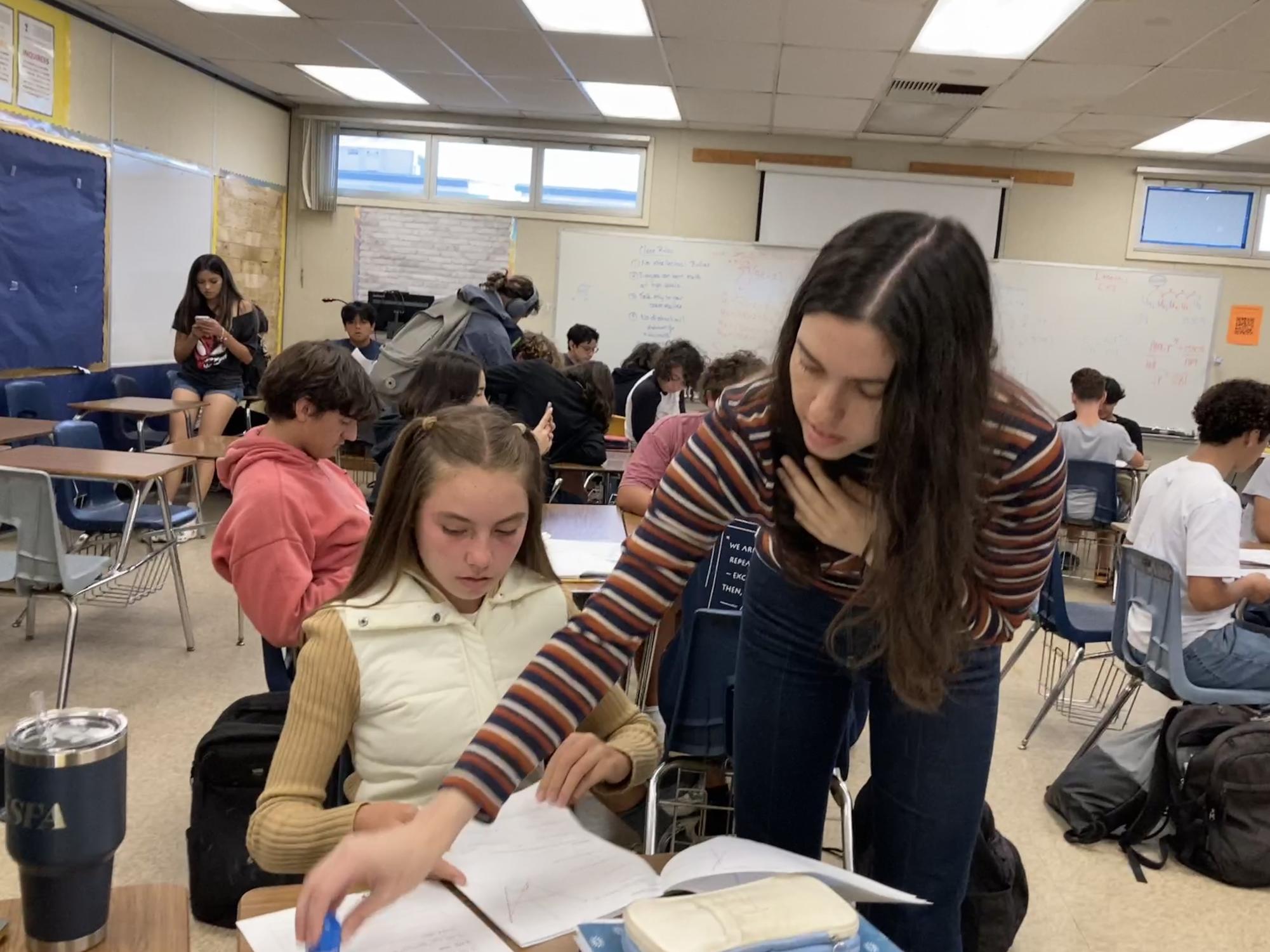 Jessica Erlenheim stamps sophomore Ella Roberts activity log.  After her daily lesson, she approaches every International Baccalaureate (IB) Analysis and Approaches (A&A) Standard level (SL) group in her class to check on student progress. 