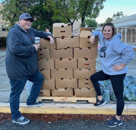 Jimmy Murphy and Ronnie Pietila-Wiggs pose next to a stack of boxes full of food to be distributed to the community. The foundation participates in many community events such as food distributions.