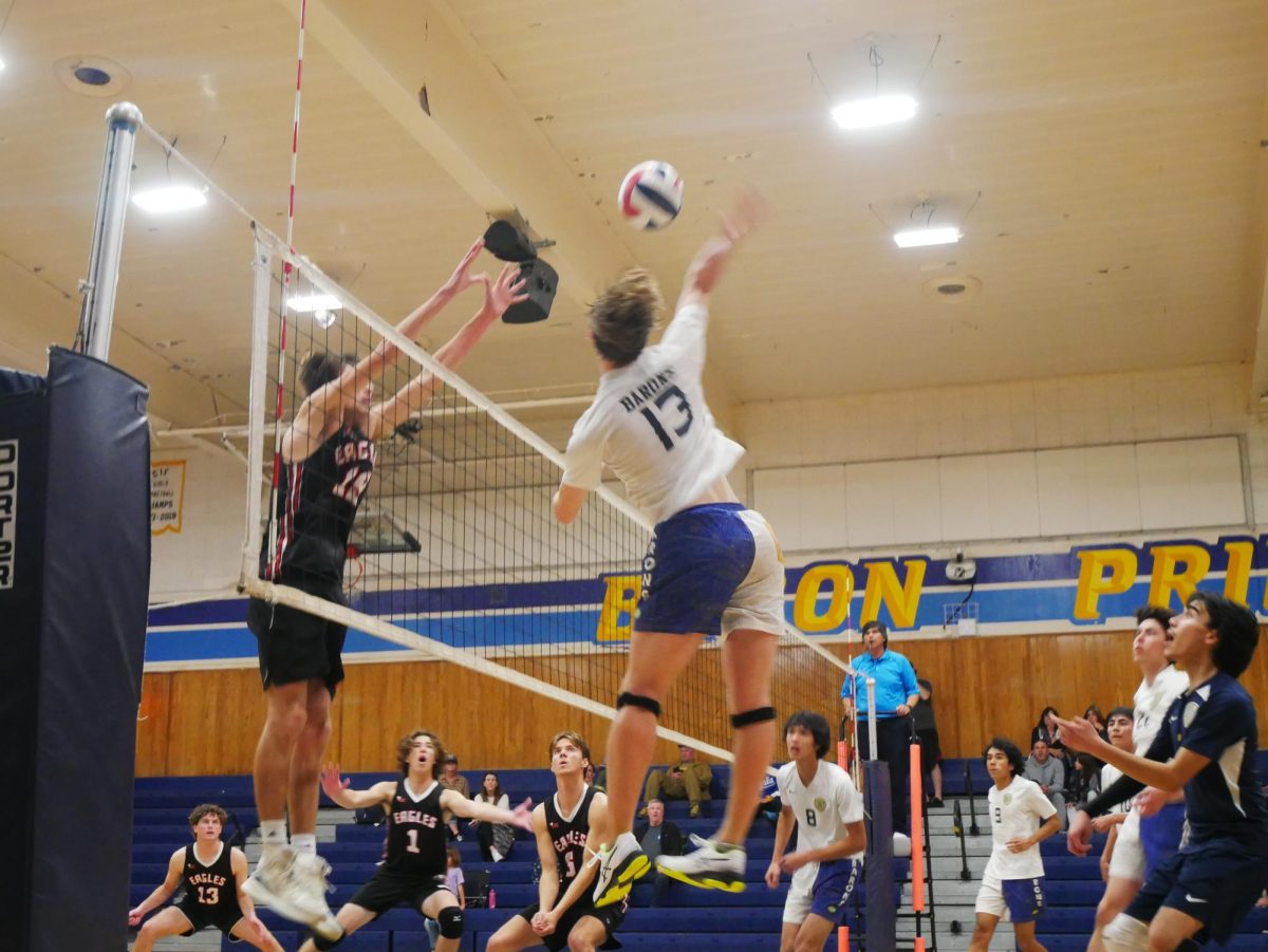 Bonita Vista High middle blocker and junior Luke Janssen (13) goes in to spike against his Santa Fe Christian (SFC) opponents. The rest of the BVH boys varsity volleyball team watch in awe as the junior goes in for the kill. 