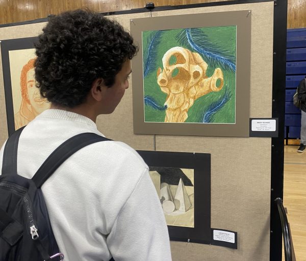 Junior Sebastian Andrade observes freshman Maisy Blanas oil pastel painting Abstraction. Blanas was one of the many students in Braunns class to have their art featured in BVH Artsfest 2024.