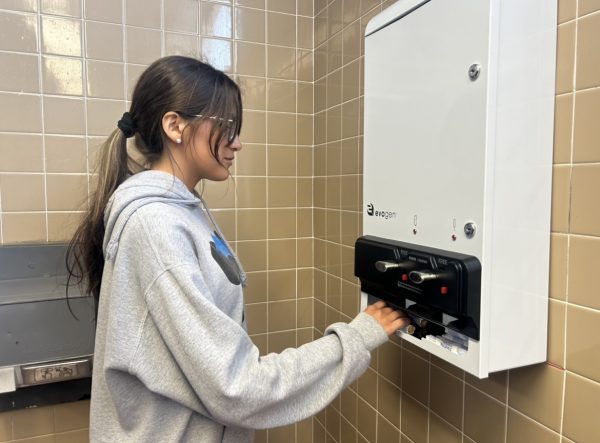 On April 8, sophomore Eugenia Carrillo Tejeda is shown grabbing a feminine product in the 700s girls bathroom. Tejada enjoys the dispensers as she does not have to bring them from home and have easy access when she needs them.