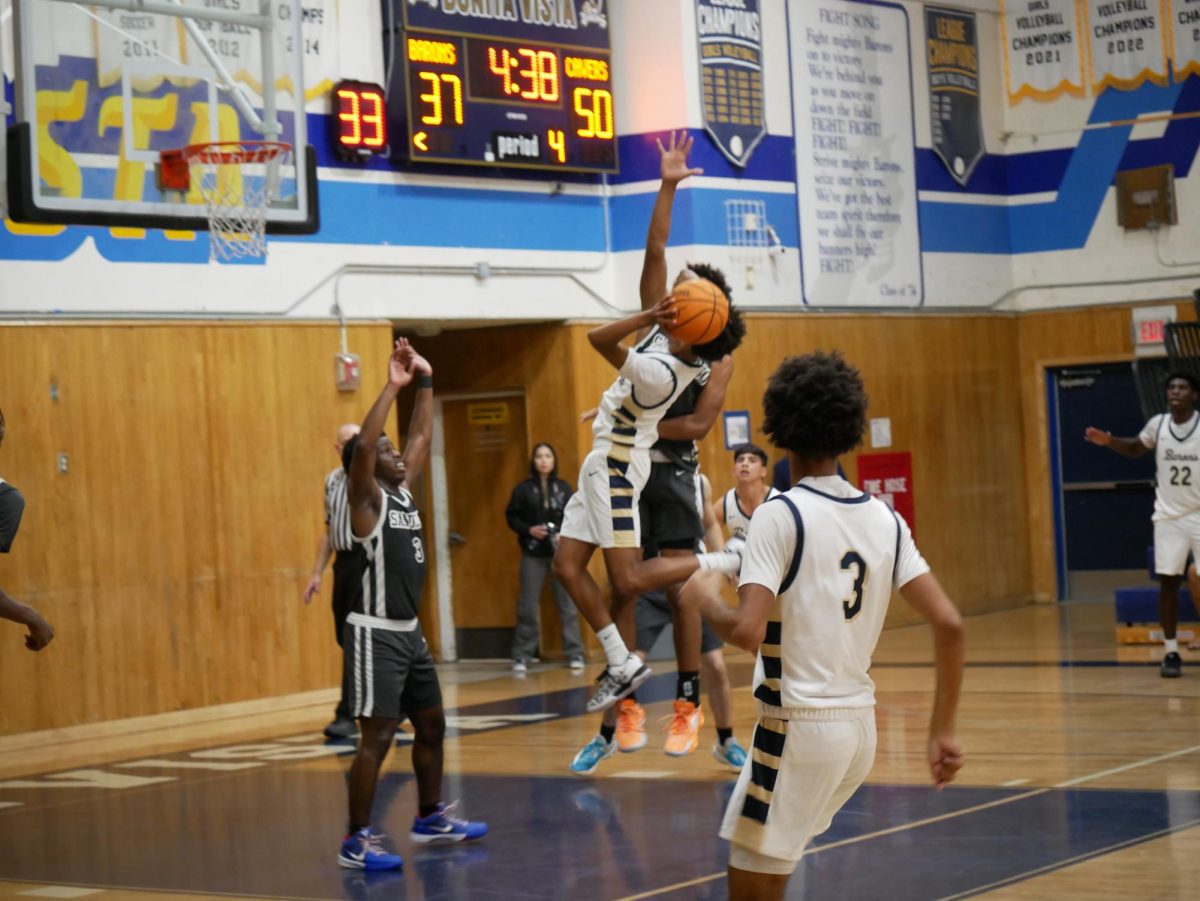 Point guard and sophomore Jerry Stokes (4) elevates past the defense making a contested layup as his teammates watch the play unfold. On Dec. 6 BVH boys' basketball played against San Diego High School (SDHS) resulting in a loss 56-59.