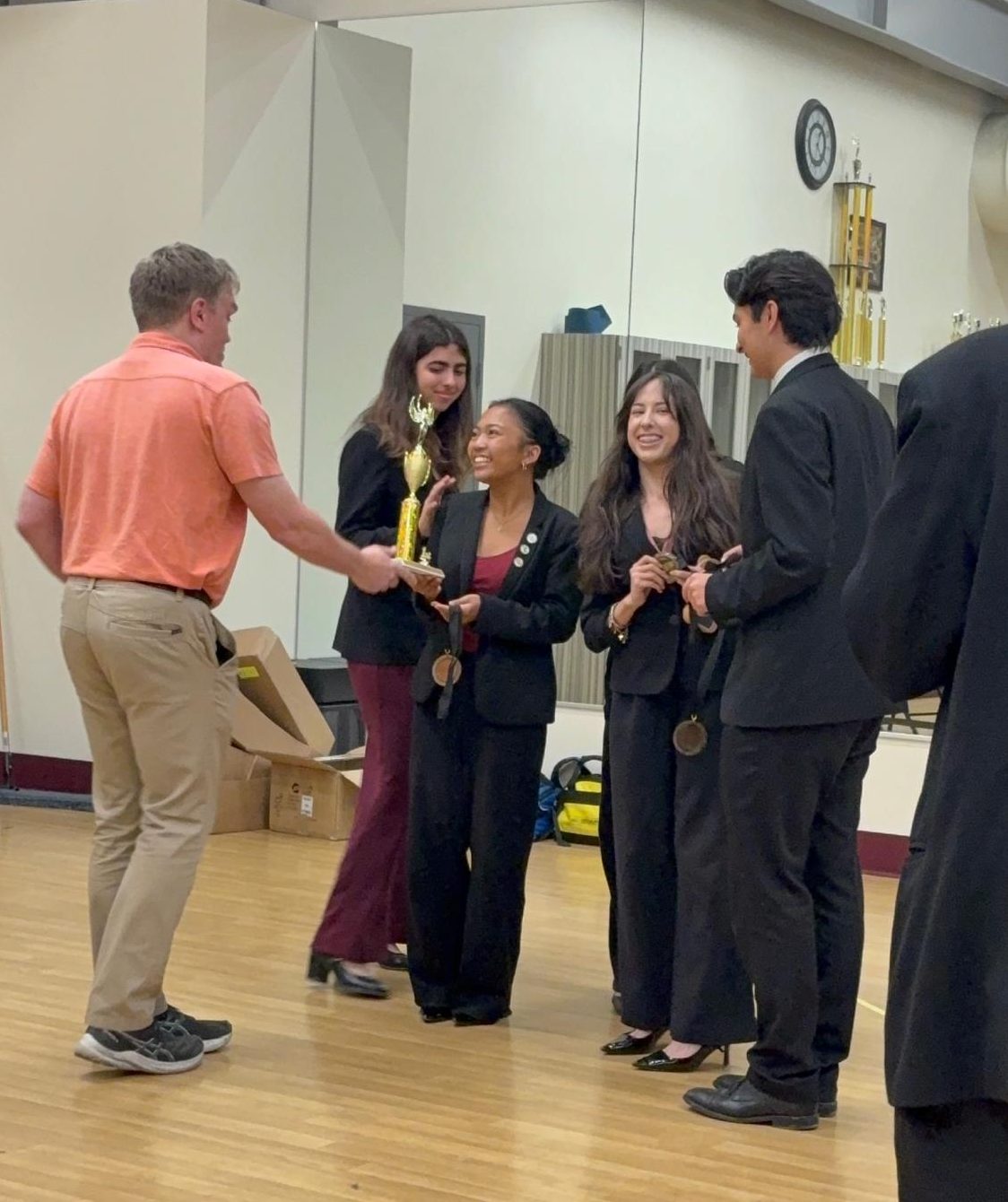 On March 29, senior Audrey Oani qualified to the National Speech & Debate Championship, to be held in Richmond, VA this summer. Oani is seen receiving the award for first place in the World Schools category, her debate partners Elizabeth Hoffman, Amanda Cortes, and Michael Finch showing gratitude and excitement alongside her. Photo provided by Audrey Oani.