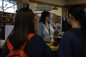 BVH librarian Adrienne Marriott assists seniors Susana Gonzalez and Isabel Arguelles at the library help desk. 